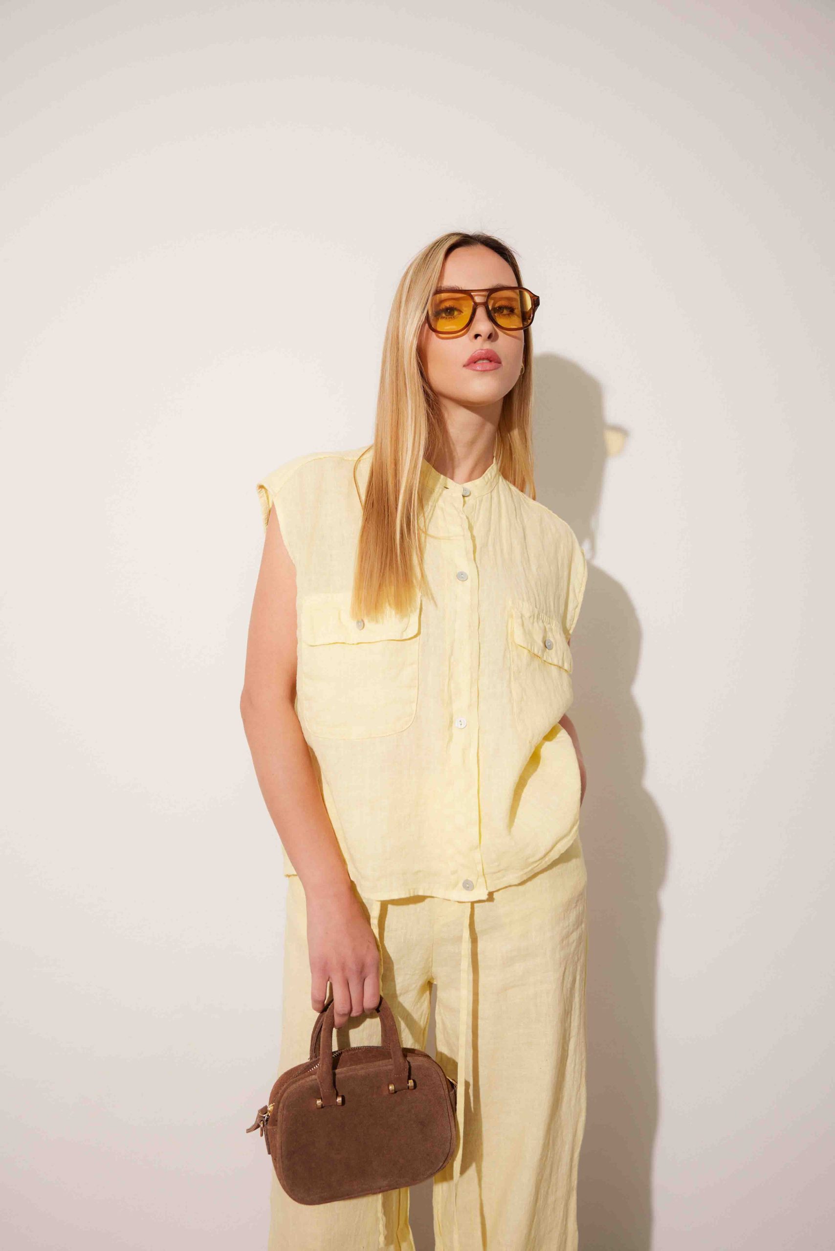 Camicia e pantalone in lino giallo chiaro con borsa in pelle