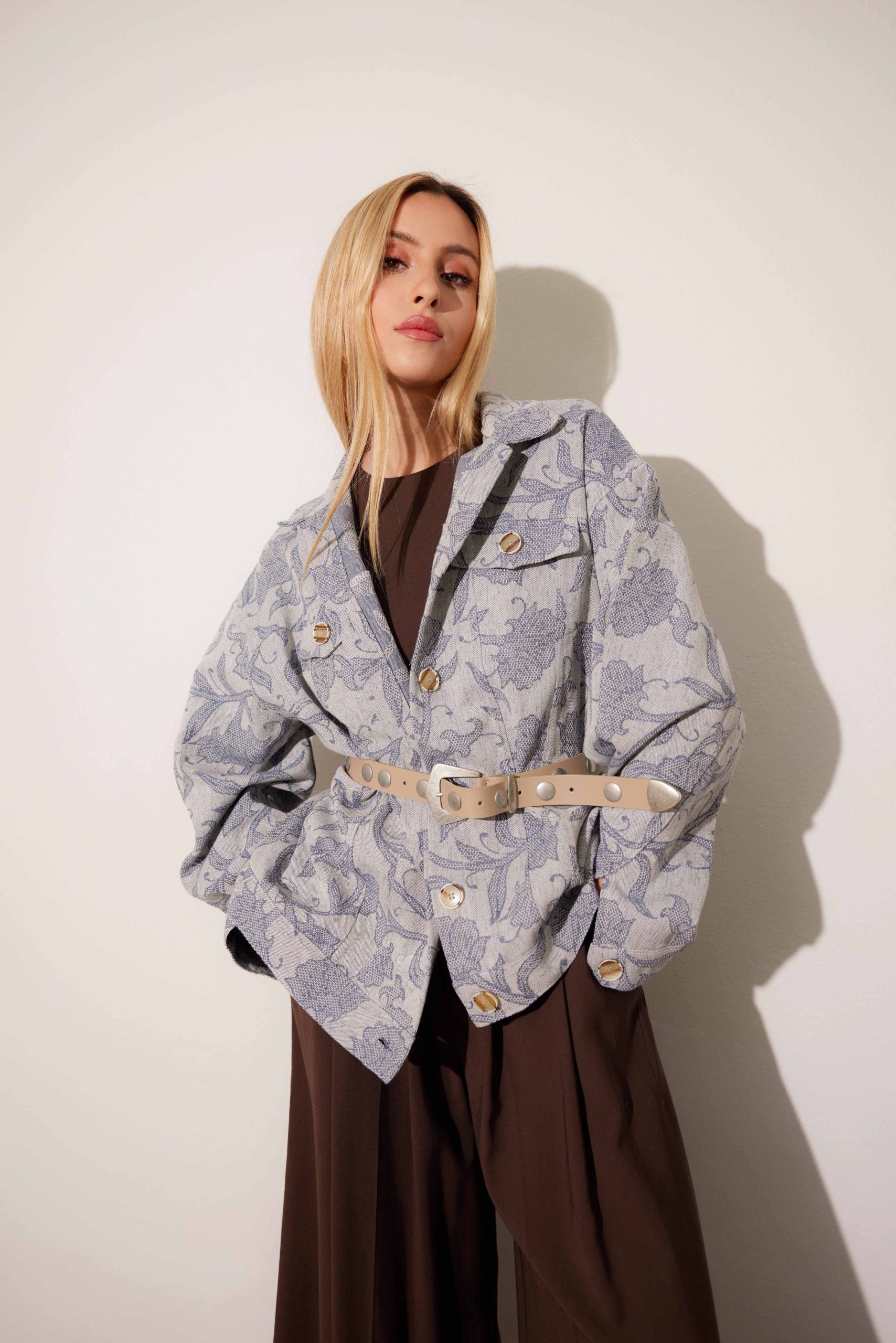 Giacca grigia con motivo floreale e cintura, pantaloni marroni